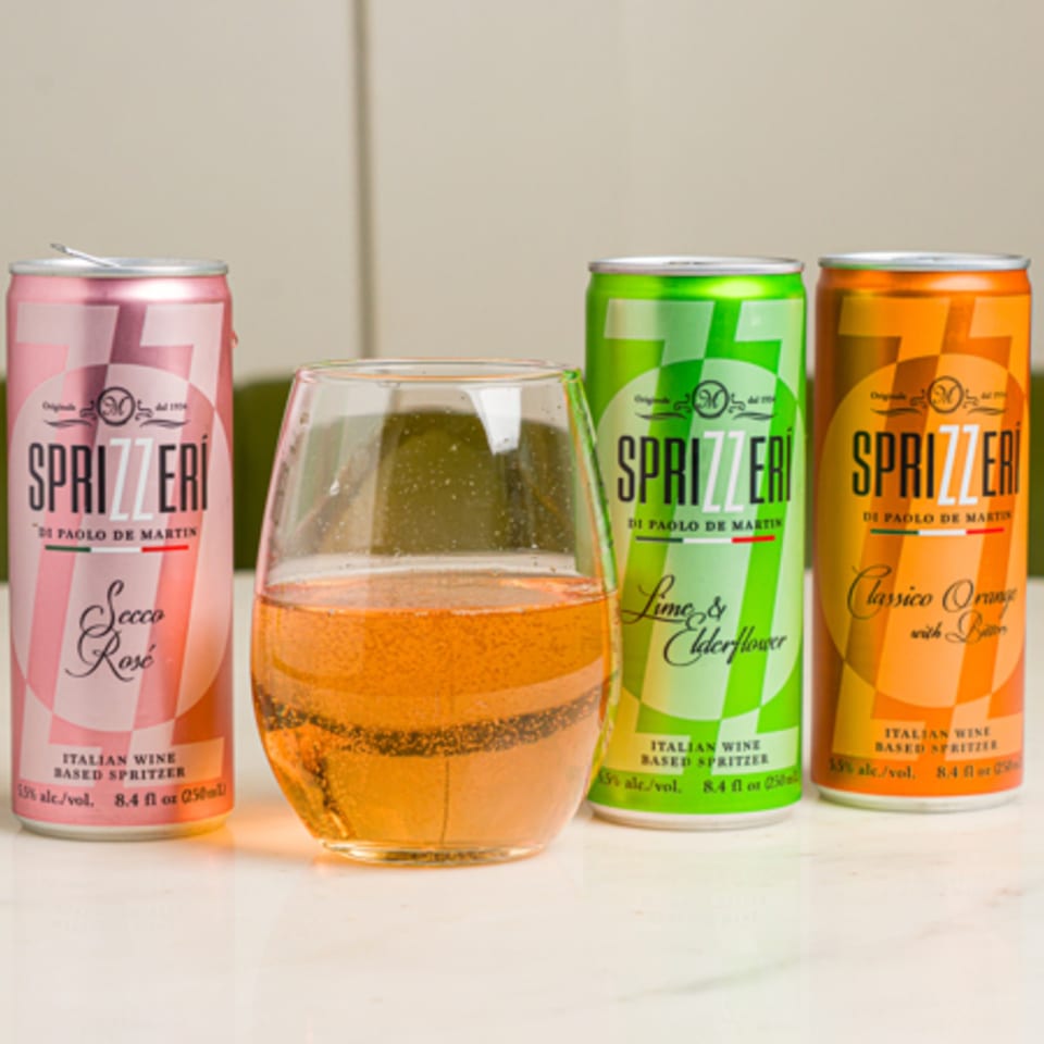 Three Sprizzeri Italian wine spritzer cans in pink, green, and orange, with a glass of rosé.