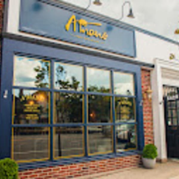 Exterior of A'mano Fresh Pasta Kitchen, a blue storefront with large windows and a brick base.