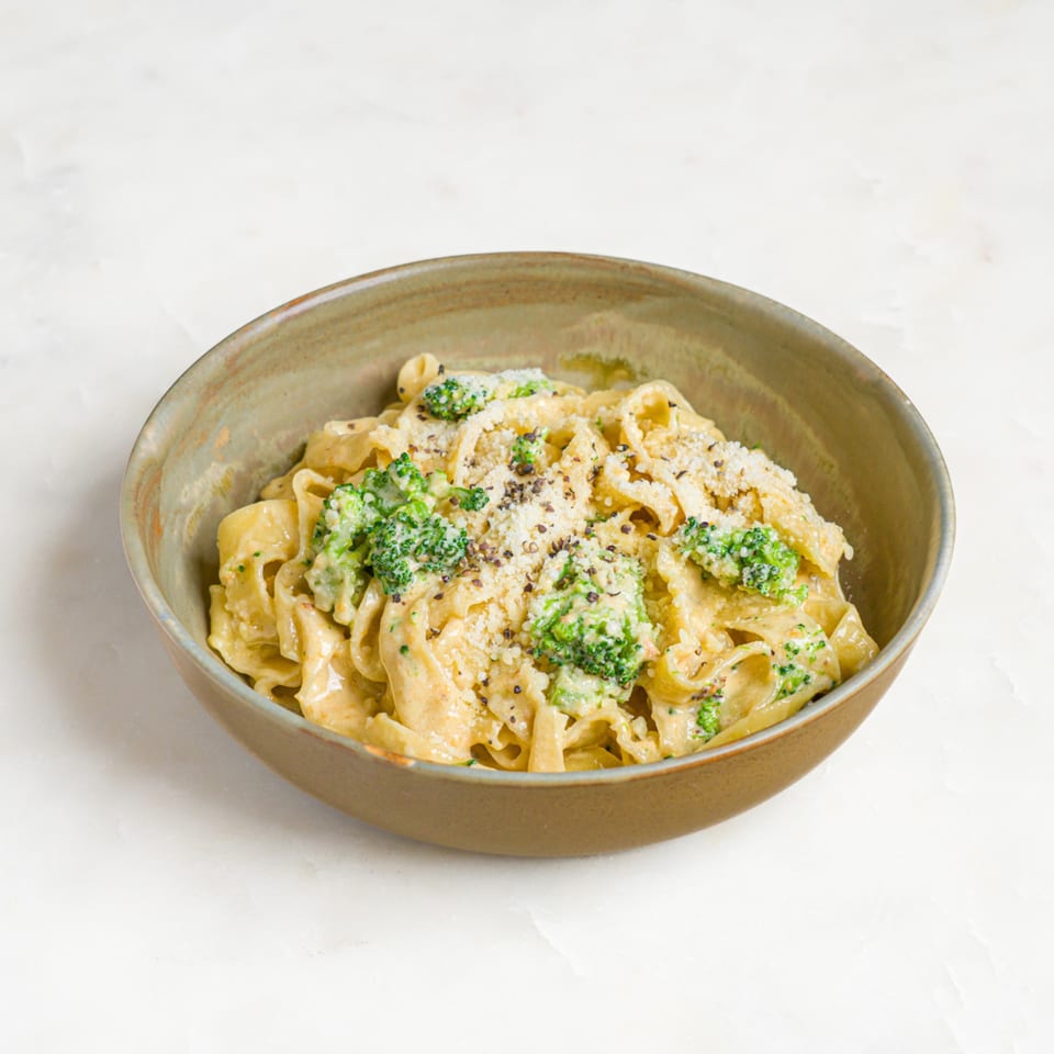 A'mano Fresh Pasta Kitchen's creamy fettuccine with broccoli, parmesan, and black pepper in a rustic bowl.